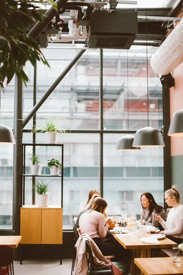 Quatre femmes dans un restaurant élégant avec des plantes en pot.